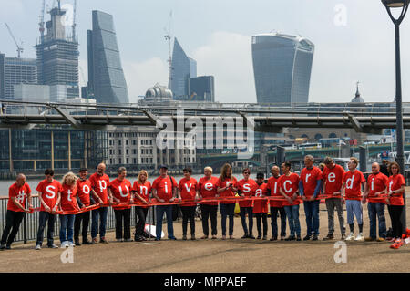 London, Großbritannien. 24. Mai 2018. Die Befürworter von Camden vereinen Gemeinschaft posieren für ein Foto auf dem Spaziergang am Flussufer in der Tate Modern, mit der Millennium Bridge und die Wolkenkratzer im Hintergrund als Teil der Unite nationalen Tag der Aktion gegen Universal Kredit. Credit: Peter Marschall/Alamy leben Nachrichten Stockfoto