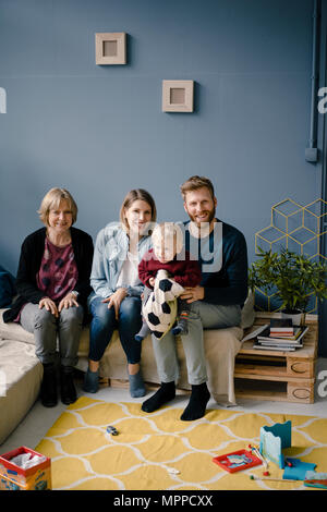 Familie im Wohnzimmer mit Sohn und Großmutter sitzen Stockfoto