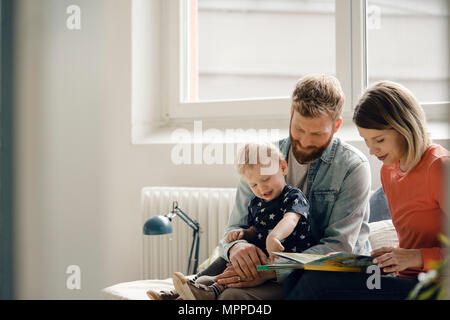 Little Boy sittiing auf dem Schoß des Vaters, der Mutter auslesen Kinderbuch Stockfoto