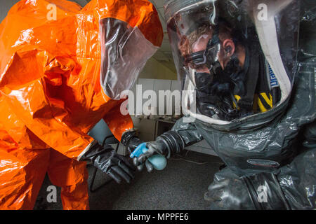 Sgt. Cory Sweetman, rechts, saniert Sgt. Koran Williams, beide mit 21 Waffen der New Jersey National Guard von Mass Destruction-Civil Support Team, Handschuhe bei einer gemeinsamen Übung in Fort Monmouth, New Jersey, April 6, 2017. Das 21 WMD-CST ist eine gemeinsame Einheit aus New Jersey National Guard Soldaten und Piloten, deren Aufgabe es ist, die zivilen Autoritäten durch die Identifizierung von chemischen, biologischen, radiologischen und nuklearen Stoffen entweder in man-made oder Naturkatastrophen. (New Jersey National Guard Foto von Mark C. Olsen/Freigegeben) Stockfoto