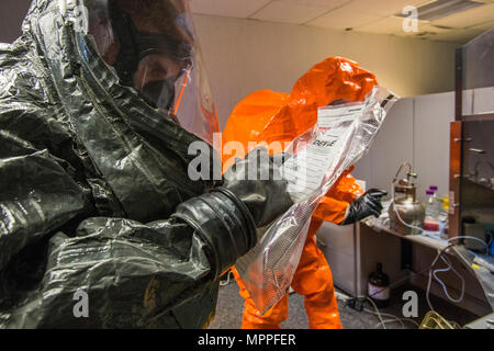 Sgt. Cory Sweetman, Links, ein Beweis Tasche beschriftet, während Sgt. Koran Williams, beide mit 21 Waffen der New Jersey National Guard von Mass Destruction-Civil Support Team, Fotos einer simulierten Lab Website bei einem gemeinsamen Training in Fort Monmouth, New Jersey, April 6, 2017. Das 21 WMD-CST ist eine gemeinsame Einheit aus New Jersey National Guard Soldaten und Piloten, deren Aufgabe es ist, die zivilen Autoritäten durch die Identifizierung von chemischen, biologischen, radiologischen und nuklearen Stoffen entweder in man-made oder Naturkatastrophen. (New Jersey National Guard Foto von Mark C. Olsen/Freigegeben) Stockfoto