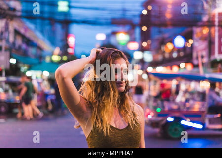 Thailand, Bangkok, junge Frau, die in der Stadt auf der Straße bei Nacht Stockfoto