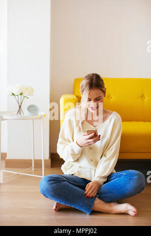 Blonde Frau zu Hause verwenden Smartphone Stockfoto