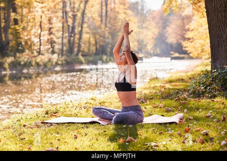 Mitte der erwachsenen Frau im Wald Üben Yoga, Meditation Stockfoto
