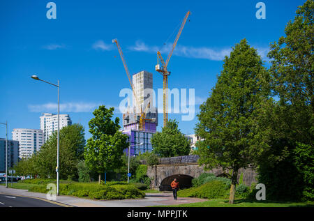 Baukräne vor blauem Himmel an einem warmen Sommertag im Zentrum von Cardiff, Wales, UK gesehen. Stockfoto