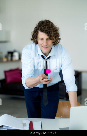 Geschäftsmann spielen Ping pong mit einem Ball und sein Handy Stockfoto