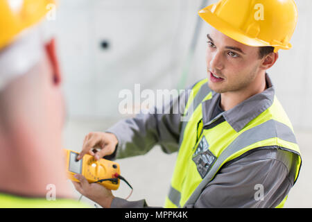 Elektriker arbeiten mit Voltmeter auf der Baustelle Stockfoto