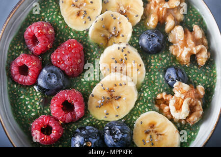 Buddha Schüssel grünem Chia Pudding mit Bananenscheiben, Blaubeeren, Himbeeren und Walnüsse Stockfoto