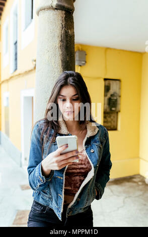 Junge Frau in eine Stadt, die ihr Smartphone prüfen Stockfoto