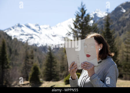 Frau mit Gesicht mit Buch, lesen Poesie in den Bergen Stockfoto