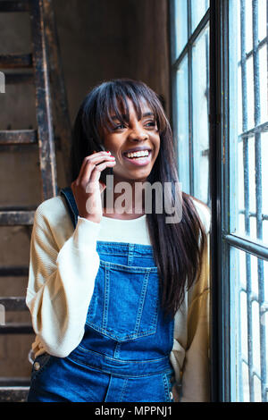 Portrait von glücklichen Frau am Telefon Blick aus Fenster Stockfoto