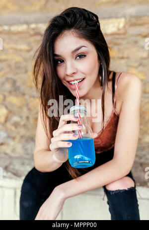 Porträt eines lächelnden brünette Frau trinkt Blaue Limonade Stockfoto