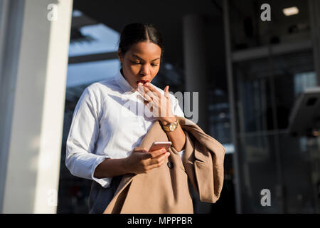 Portrait von schockiert Geschäftsfrau Lesen von E-Mails auf Ihrem Mobiltelefon Stockfoto