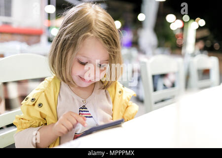 Portrait von lächelnden Mädchen in einem Restaurant spielen mit Smartphone sitzen Stockfoto