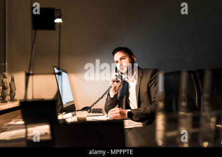 Geschäftsmann am Telefon im Büro bei Nacht Stockfoto