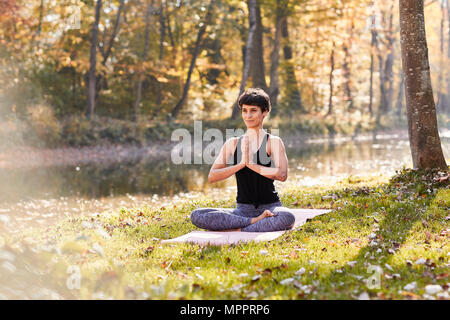 Mitte der erwachsenen Frau im Wald Üben Yoga, Meditation Stockfoto