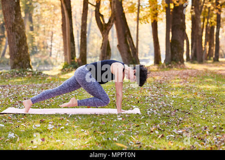 Mitte der erwachsenen Frau im Wald Üben Yoga, Kletterer Übung Stockfoto