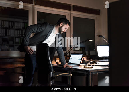 Unternehmer stehen in Büro in der Nacht auf der Suche nach Tablet Stockfoto