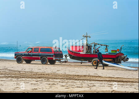 Pacific City, Oregon, USA - Juli 2, 2015: Ein roter und schwarzer 4-Rad SUV zieht ein Ruderboot Boot, mit der gleichen Farbe, auf dem Trailer. Ein Paddel Stockfoto