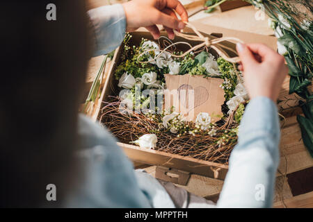 Frau Anordnen von Blumen in einer Box, Teilansicht Stockfoto