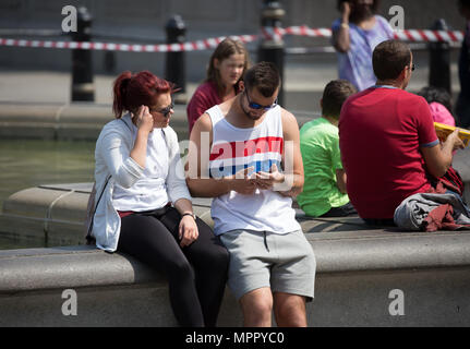 Die Menschen in der Sonne auf dem Trafalgar Square in London Stockfoto