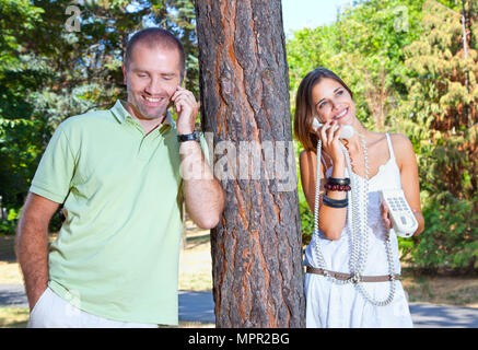 Junge schöne Paar Mann und Frau im Gespräch per Telefon im Park. Satz für den Sommer Stockfoto