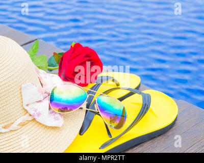 Sonnenbrille mit Rote rose Blumen, Sommer Hut und Flip Flops durch den Pool. Urlaub und Entspannung, Sommer Travel Concept. Stockfoto