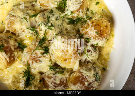 Baby neue Kartoffeln mit saurer Sahne und Käse Sauce in der Platte - Ansicht von oben Stockfoto