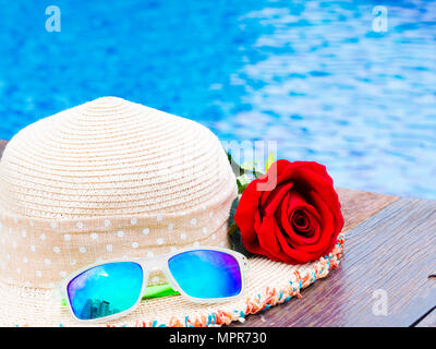 Red rose Blüten mit Sommer Hut und Sonnenbrille am Pool. Urlaub und Entspannung, Sommer Travel Concept. Stockfoto