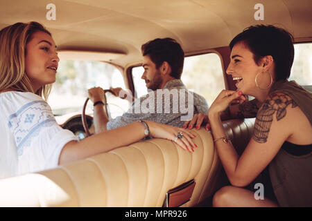 Frauen tratschen im Auto während man fahren auf Road Trip. Freunde auf einer Reise durch ein Auto reisen. Stockfoto
