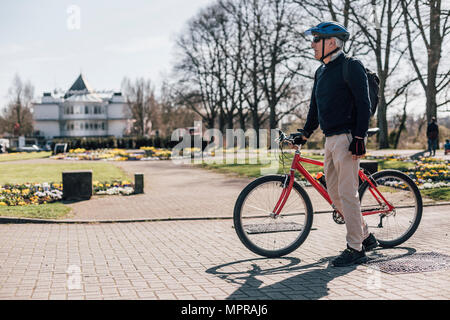 Älterer Mann mit Fahrrad in einem Park Stockfoto