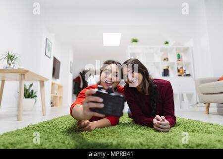 Zwei glückliche junge Frauen, die auf dem Boden liegend in Coworking Space ein selfie Stockfoto