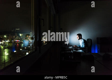 Unternehmer Arbeiten am Computer im dunklen Büro Stockfoto
