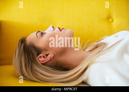 Blonde Frau auf dem Sofa liegend Stockfoto