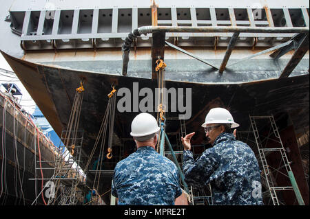 SASEBO, Japan (11. April 2017) Cmdr. Severn Stevens, kommandierender Offizier der Whidbey Island-Klasse amphibische Landung dock Schiff USS Germantown (LSD 42), rechts, spricht mit Vice Adm. Tom Rowden, Commander, Naval Surface Force Pazifik, während eines Besuchs in der Trocken-Schiff angedockt. Rowden besucht Flotte Aktivitäten Sasebo, wo viele der eingesetzten Amphibious Force 7 Flotte stationiert sind, freuen Sie sich auf besser-einsatz Bereitschaft Herausforderungen verstehen und die Grundsätze der neuen Oberfläche kraft Strategie teilen. Stockfoto