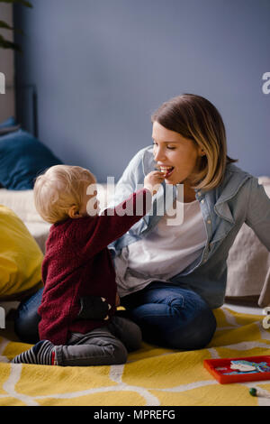 Mutter spielt mit ihrem Baby Sohn, der Fütterung ist Ihr Stockfoto