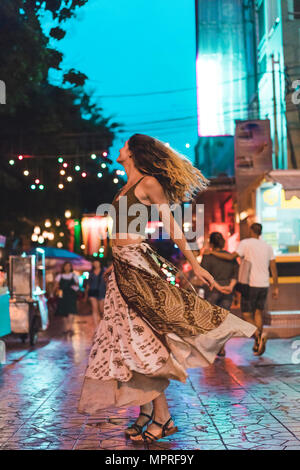 Thailand, Bangkok, junge Frau in der Stadt, Tanzen auf der Straße bei Nacht Stockfoto
