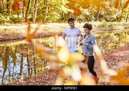 Paar Jogging auf autumnally Waldweg Stockfoto