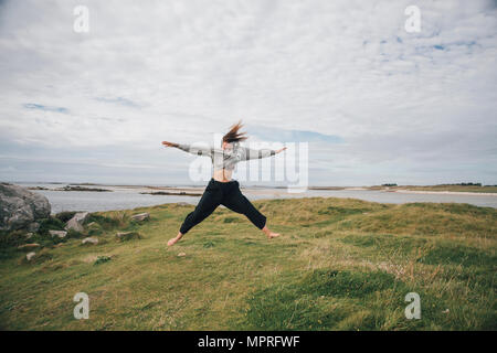 Frankreich, Bretagne, Landeda, Dünen de Sainte-Marguerite, junge Frau an der Küste springen Stockfoto