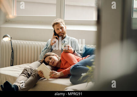 Glückliches Paar Lesen und Kuscheln zu Hause Stockfoto