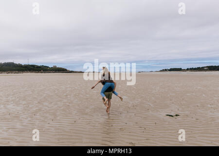 Frankreich, Bretagne, Guisseny, junge Mann laufen, die freundin Huckepack am Strand Stockfoto