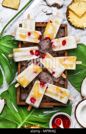 Pina Colada Eis am Stiel mit kandierten Kirschen und Ananas auf Blatt Stockfoto