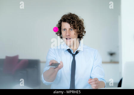 Geschäftsmann spielen Ping pong mit einem Ball und sein Handy Stockfoto