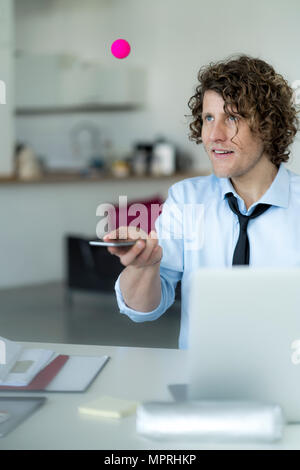 Geschäftsmann spielen Ping pong mit einem Ball und sein Handy Stockfoto