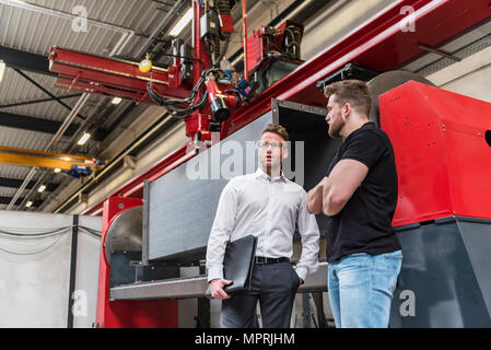 Zwei Männer stehen und sprechen über Factory Shop Boden Stockfoto