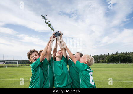 Junge Fußball-Spieler jubeln mit Schale Stockfoto