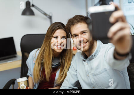 Zwei lächelnde casual Kollegen im Büro einen selfie Stockfoto