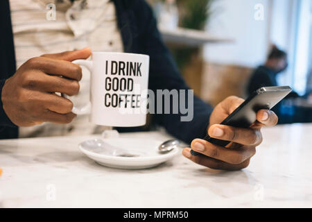 Nahaufnahme der Mann mit Tasse Kaffee in einem Cafe mit Handy Stockfoto