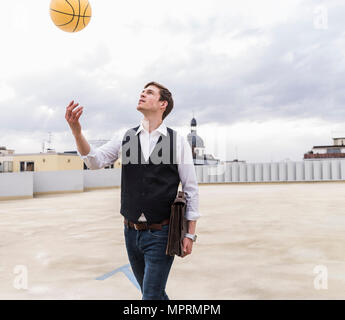 Geschäftsmann oben werfen Basketball am Parkplatz Garage Stockfoto