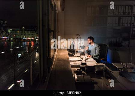 Unternehmer Arbeiten am Computer im Büro bei Nacht Stockfoto